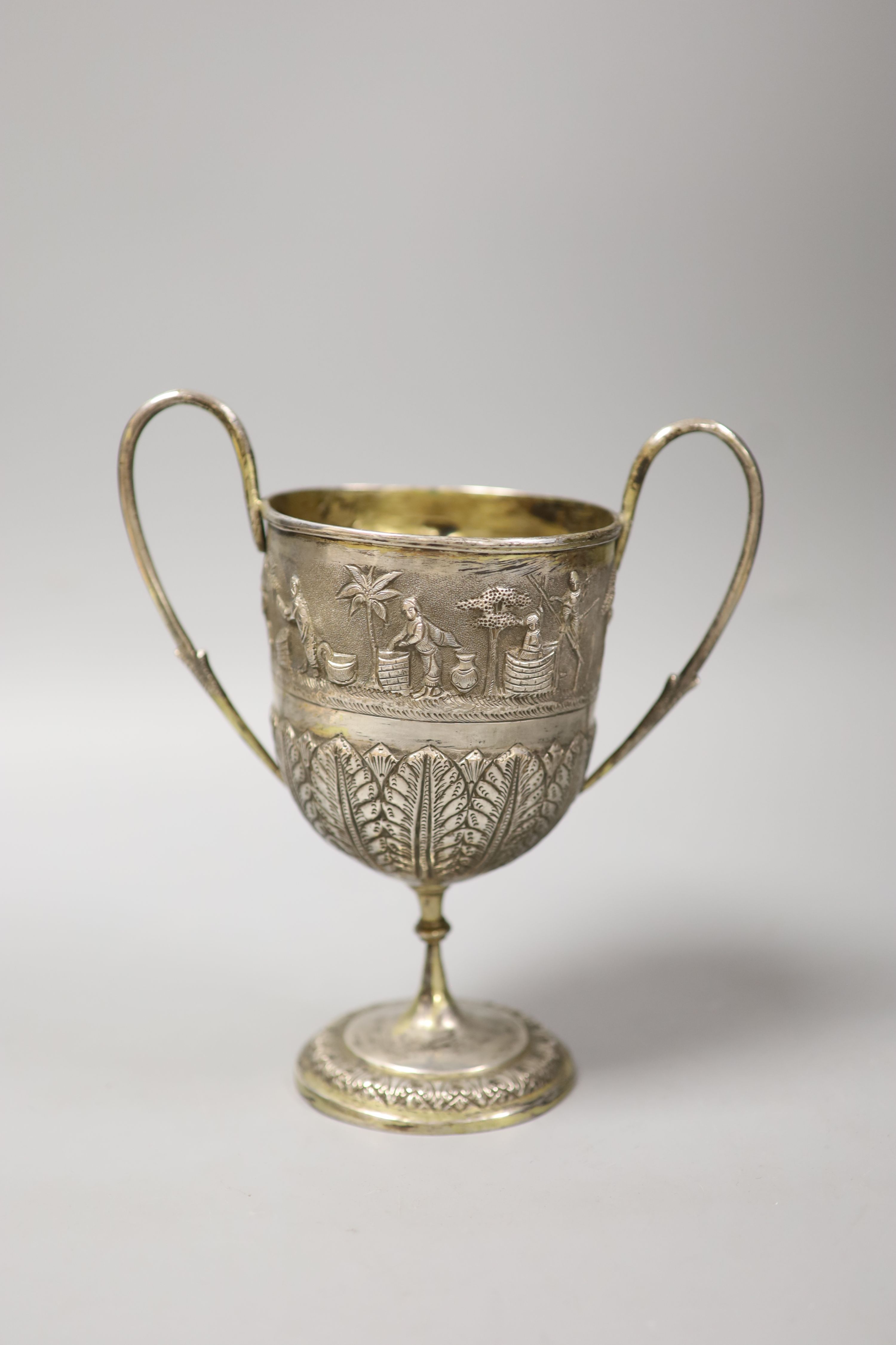 An embossed Indian white metal two handled pedestal trophy cup, height 22.2cm, 12.5oz.